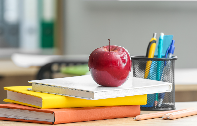 An apple on a stack of school textbooks