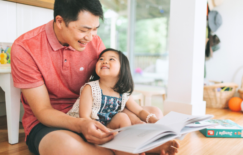 Asian man reading with toddler