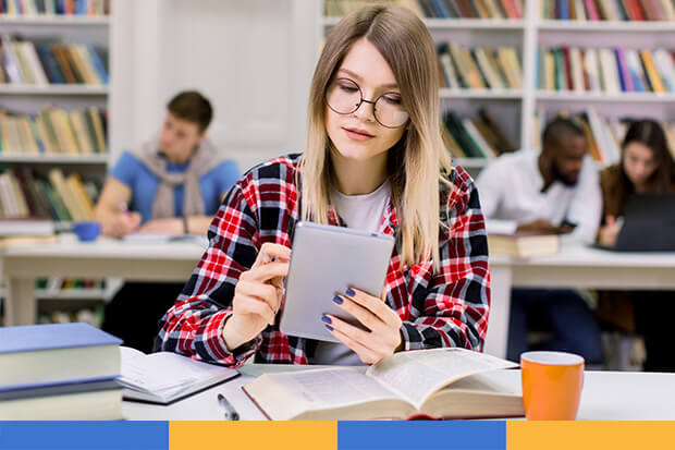 female student reading tablet in library