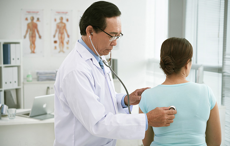 male doctor listening to woman's lungs with stethscope