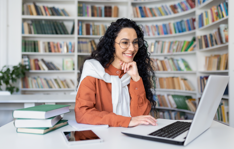 Librarian smiling at her computer with book shelves behind her