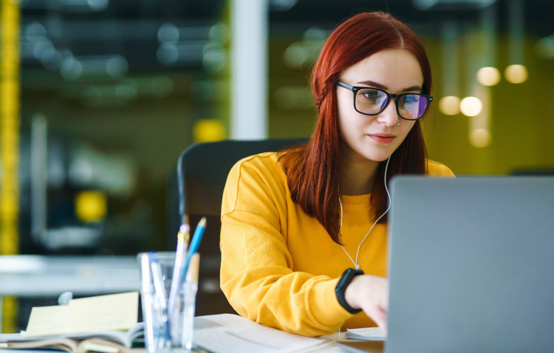 Female researching on her laptop while sitting at a desk