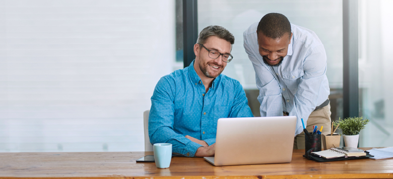 Two employees sharing a laptop at a desk