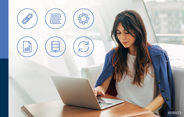 Calm and peaceful young woman wearing a blue jacket over her back while working at table near window and typing on keyboard of laptop alone in a room. Six icons in corner.