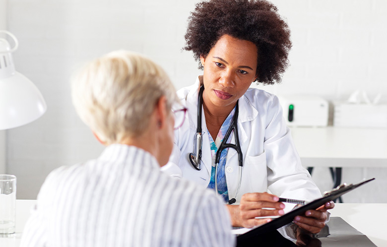 Image of a female nurse looking at a chart while consulting with a patient