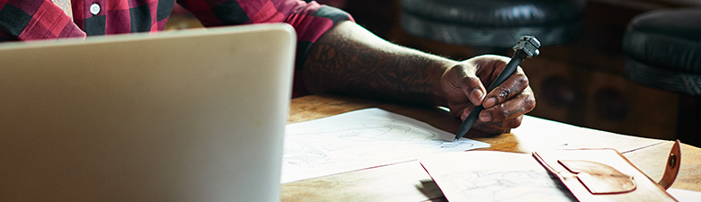 Person sitting at desk in front of laptop and writing.