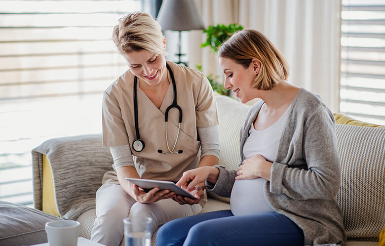 female healthcare worker discussing showing pregnant woman tablet