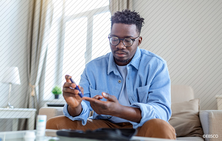 Man sitting down at home pricking his finger